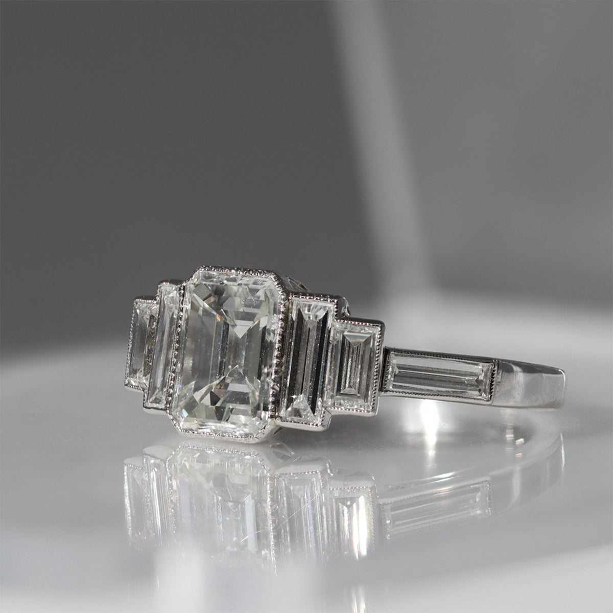 An Elegant Emerald-cut Diamond Ring with side baguettes set in Platinum reflection view